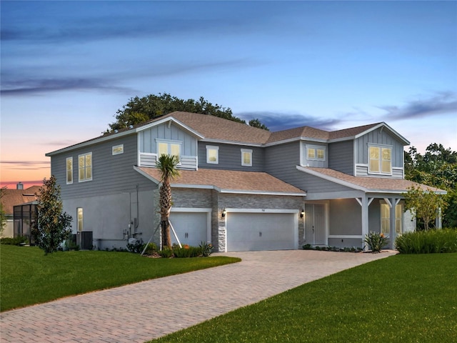 view of front facade featuring a garage, cooling unit, and a yard