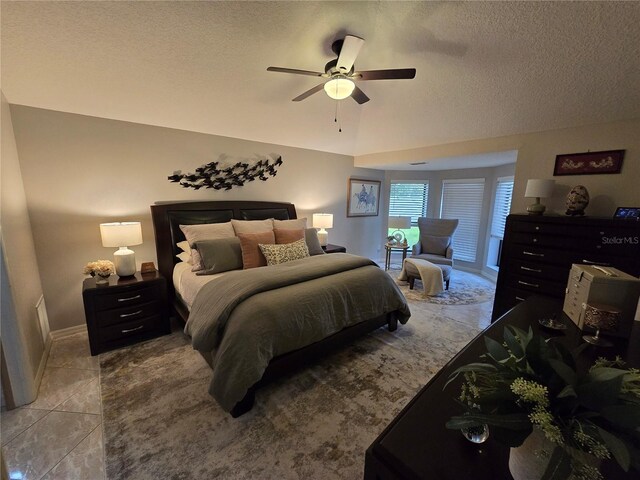 tiled bedroom with ceiling fan and a textured ceiling