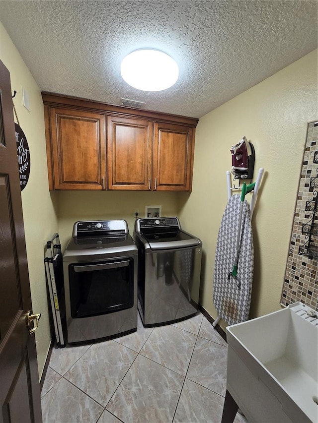 laundry area with a textured ceiling, light tile patterned floors, sink, and washing machine and clothes dryer