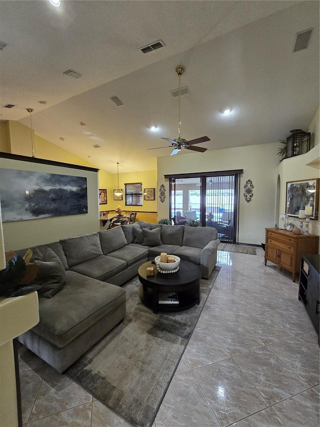 living room with a textured ceiling, ceiling fan, light tile patterned floors, and vaulted ceiling