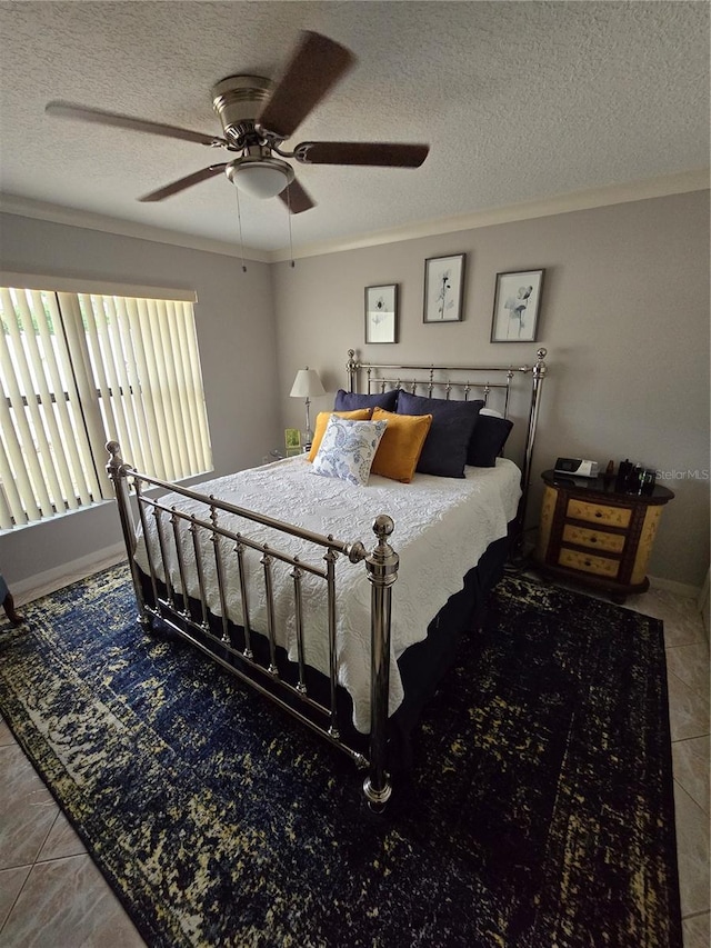 bedroom with a textured ceiling, ceiling fan, crown molding, and tile patterned floors