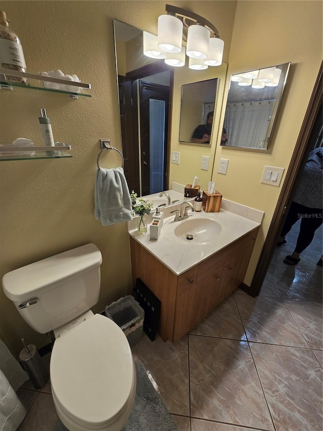 bathroom featuring toilet, a chandelier, vanity, and tile patterned floors