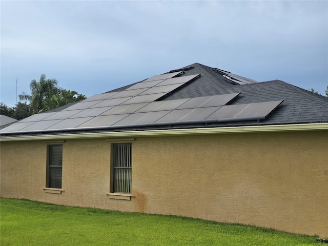 rear view of house with a lawn and solar panels