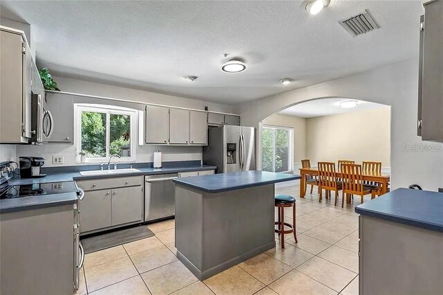 kitchen featuring light tile patterned floors, sink, gray cabinets, appliances with stainless steel finishes, and a center island