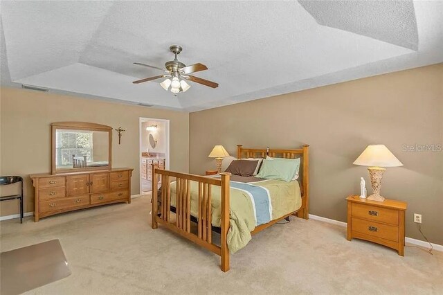 carpeted bedroom featuring ceiling fan, a raised ceiling, a textured ceiling, and ensuite bathroom