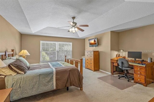 carpeted bedroom with ceiling fan, a textured ceiling, and a tray ceiling