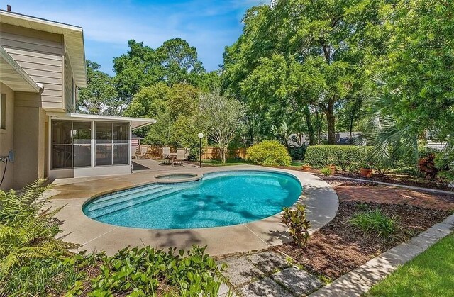 view of swimming pool with a sunroom, a patio, and an in ground hot tub