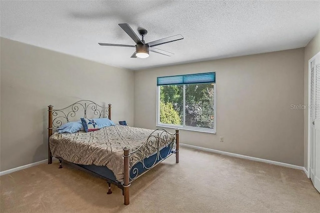 bedroom featuring ceiling fan, light colored carpet, and a textured ceiling