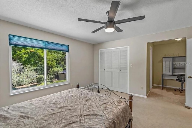 carpeted bedroom featuring ceiling fan, a closet, and a textured ceiling