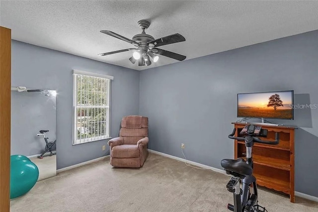 sitting room featuring ceiling fan, light colored carpet, and a textured ceiling