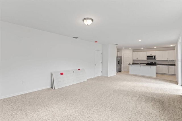 unfurnished living room with sink and light carpet