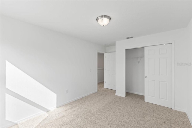 unfurnished bedroom featuring a closet and light colored carpet