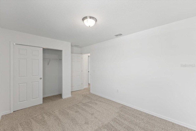 unfurnished bedroom featuring a closet and light colored carpet