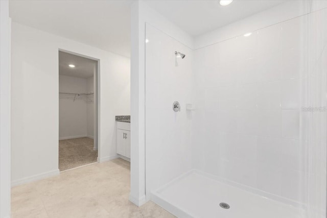 bathroom with tiled shower and vanity