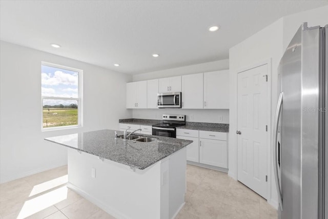 kitchen with white cabinets, appliances with stainless steel finishes, a kitchen island with sink, and sink