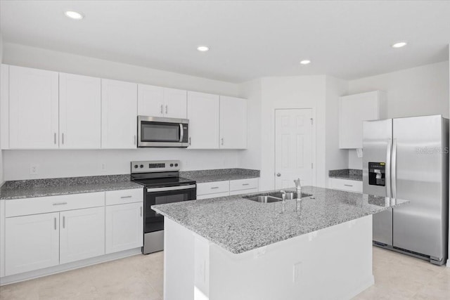 kitchen with sink, light stone countertops, appliances with stainless steel finishes, a center island with sink, and white cabinets