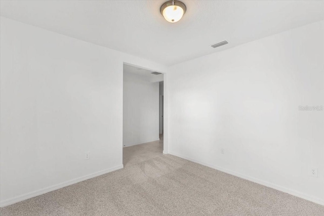 unfurnished room featuring baseboards, visible vents, and carpet