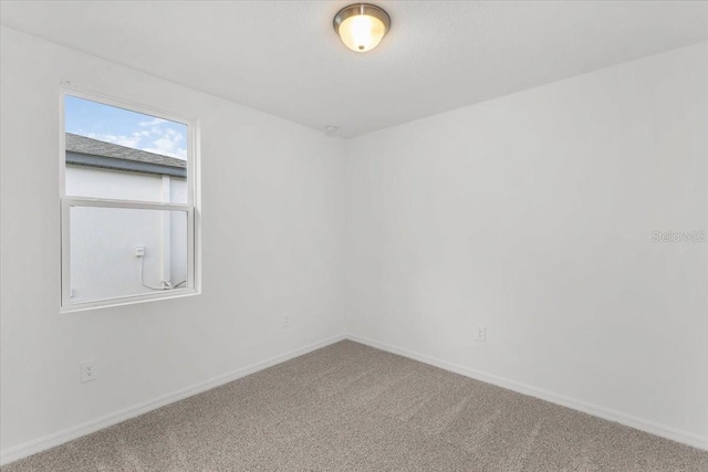 empty room with baseboards and carpet