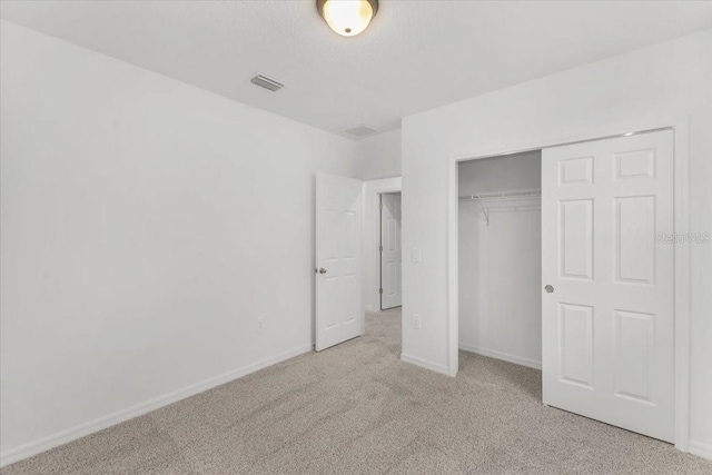 unfurnished bedroom with a closet, carpet, visible vents, and baseboards