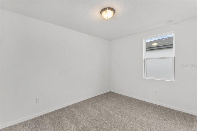 carpeted spare room featuring baseboards