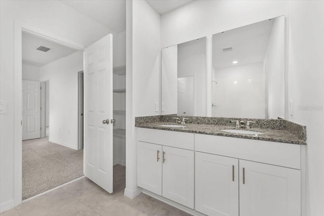 bathroom with baseboards, a sink, visible vents, and double vanity