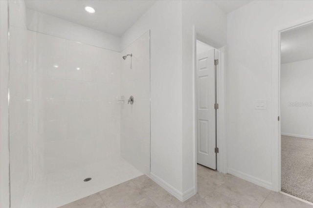 bathroom featuring a tile shower, tile patterned flooring, and baseboards