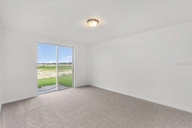 carpeted spare room featuring baseboards