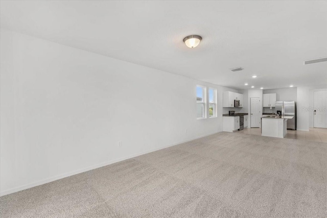 unfurnished living room with light carpet, baseboards, visible vents, and recessed lighting