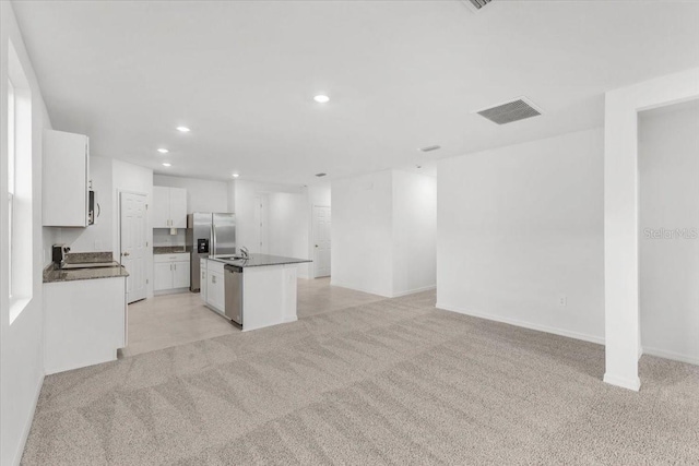 kitchen featuring dark countertops, open floor plan, a center island with sink, appliances with stainless steel finishes, and recessed lighting