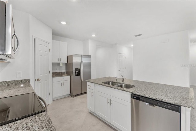kitchen featuring white cabinets, an island with sink, stainless steel appliances, a sink, and light stone countertops