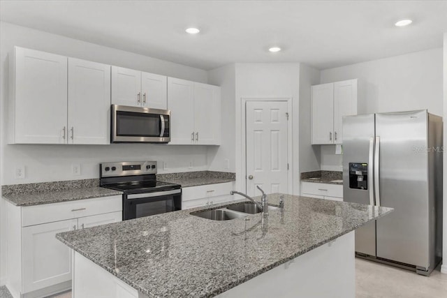 kitchen featuring stone countertops, appliances with stainless steel finishes, white cabinetry, and a sink