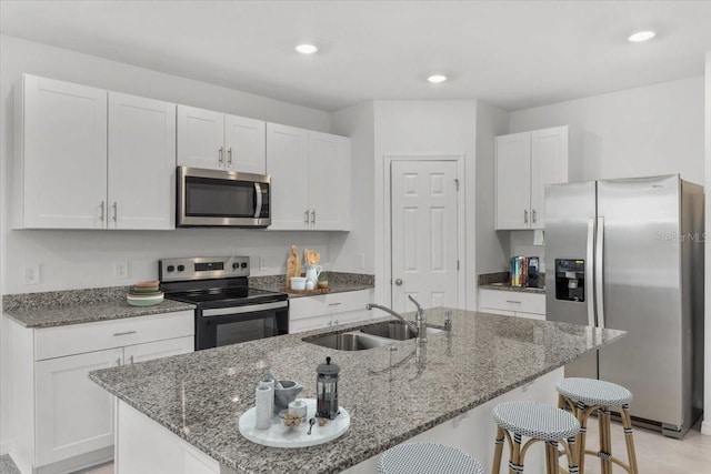 kitchen featuring a kitchen bar, white cabinets, appliances with stainless steel finishes, and a sink