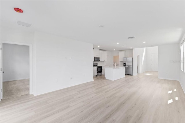 unfurnished living room with sink and light wood-type flooring