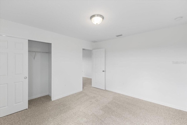 unfurnished bedroom featuring light colored carpet and a closet