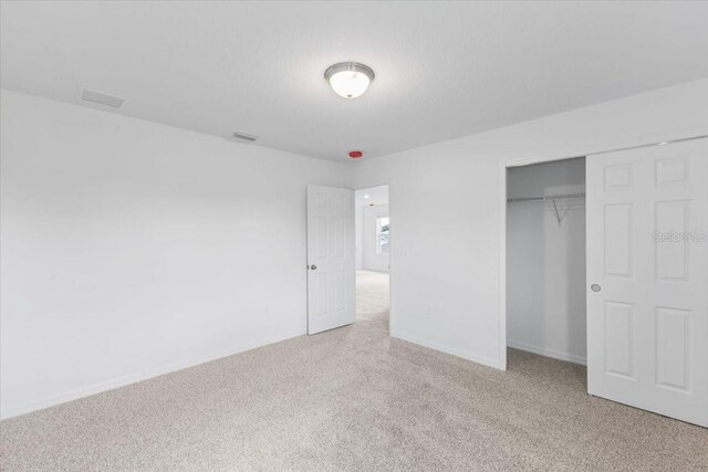 unfurnished bedroom featuring a closet and light colored carpet