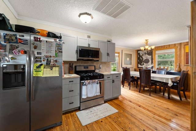 kitchen featuring appliances with stainless steel finishes, a notable chandelier, light hardwood / wood-style flooring, and gray cabinetry