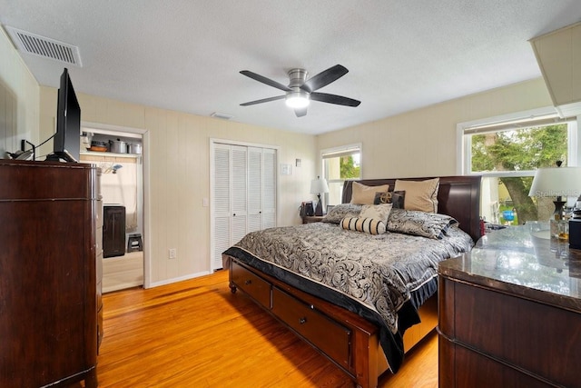 bedroom with a textured ceiling, a closet, ceiling fan, and light wood-type flooring