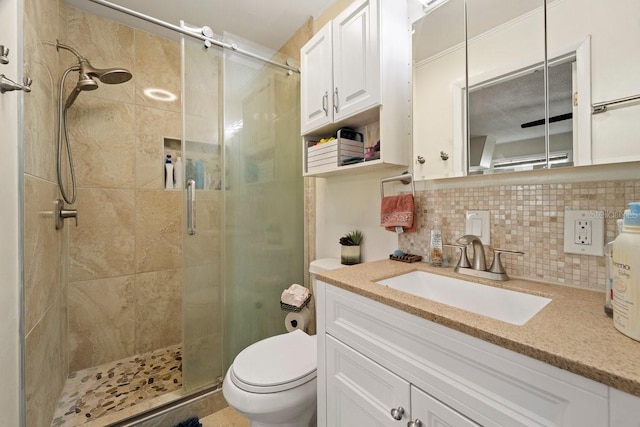 bathroom featuring tasteful backsplash, toilet, a shower with shower door, and vanity