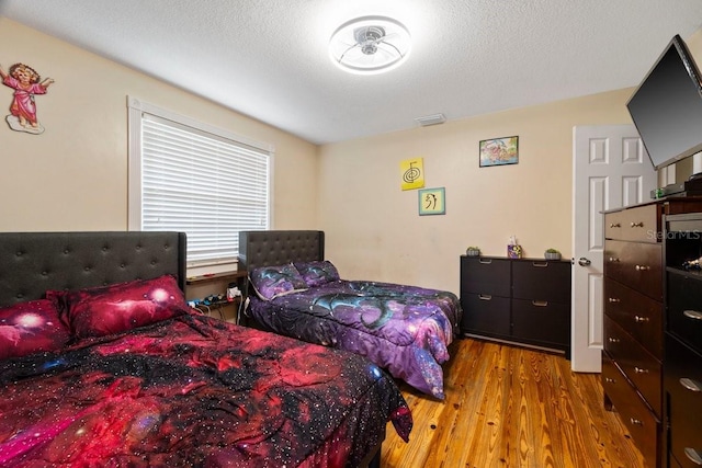 bedroom with light wood-type flooring and a textured ceiling