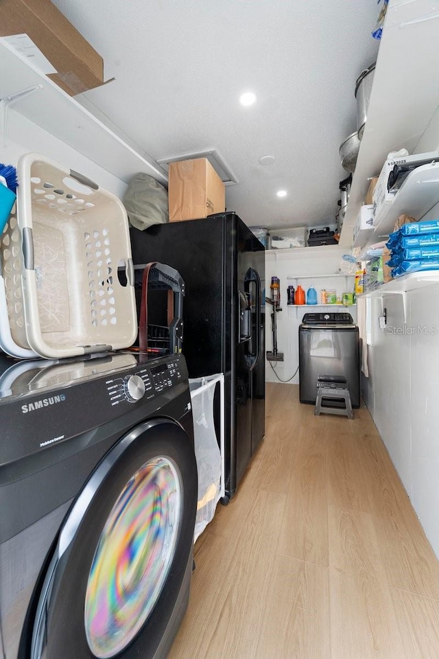 laundry room with washer / dryer and light wood-type flooring