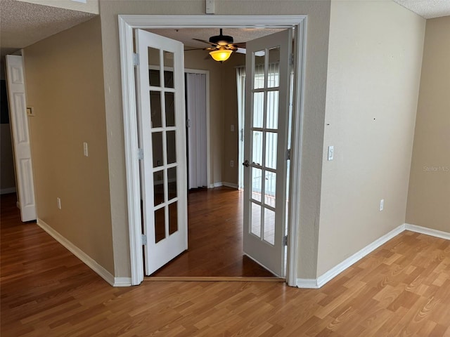 interior space with a textured ceiling, french doors, and wood-type flooring