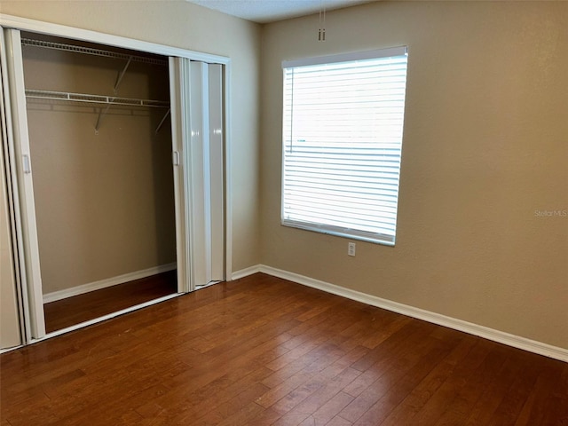 unfurnished bedroom with a closet and hardwood / wood-style floors