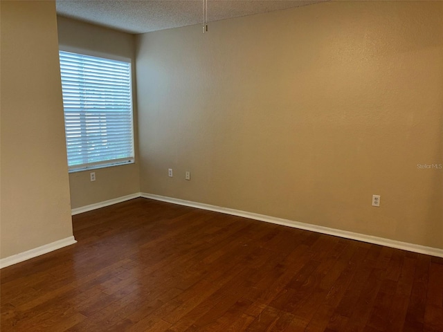 unfurnished room featuring a textured ceiling and dark hardwood / wood-style flooring