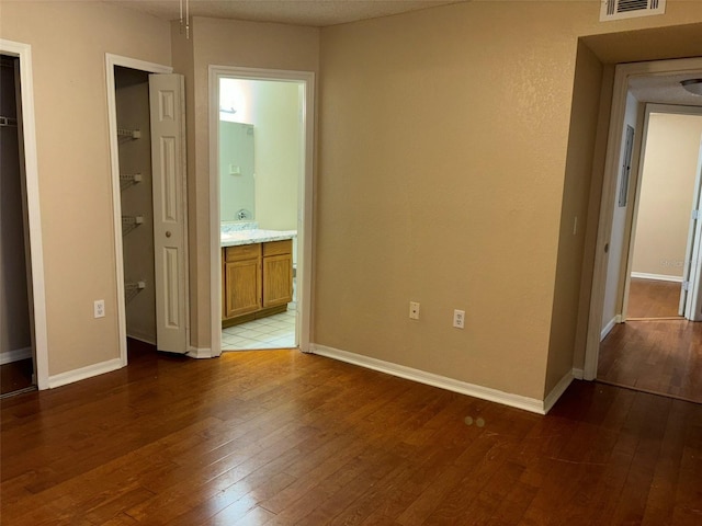 unfurnished bedroom with ensuite bath and tile patterned floors