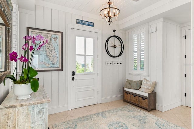 tiled entrance foyer with wood walls and an inviting chandelier