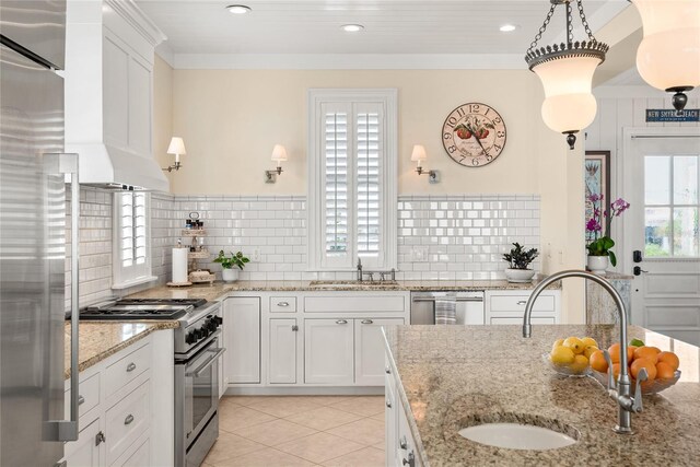 kitchen with light stone countertops, appliances with stainless steel finishes, hanging light fixtures, sink, and white cabinets