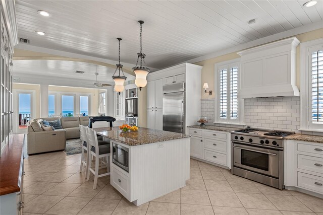 kitchen featuring white cabinetry, built in appliances, a center island, and ceiling fan