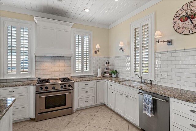 kitchen featuring stone countertops, light tile patterned floors, stainless steel appliances, sink, and white cabinetry