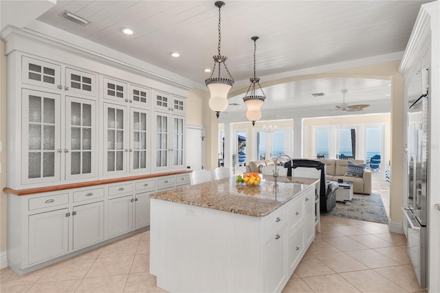 kitchen with pendant lighting, white cabinetry, an island with sink, and ceiling fan