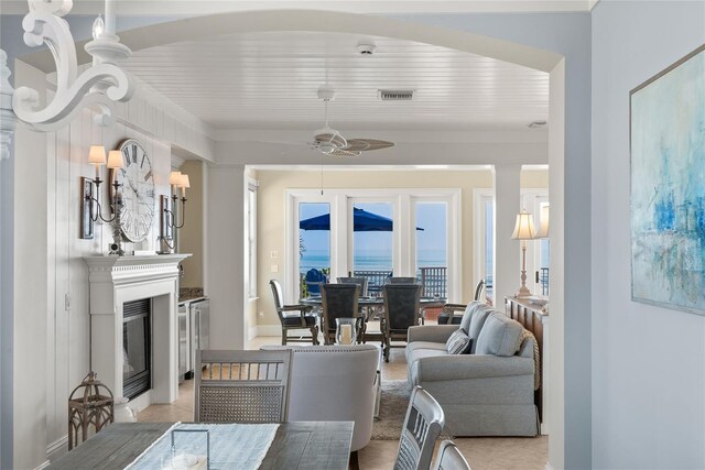 carpeted living room featuring ceiling fan with notable chandelier and a water view